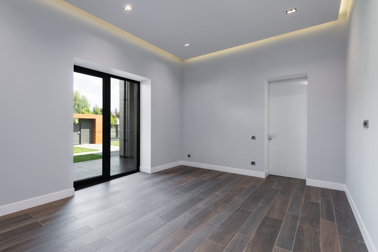 How Professional Ceiling Installation Transforms Your Space Interior of spacious room with laminate flooring big glass doors viewing terrace and white walls in daylight